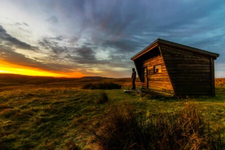 man standing beside brown house